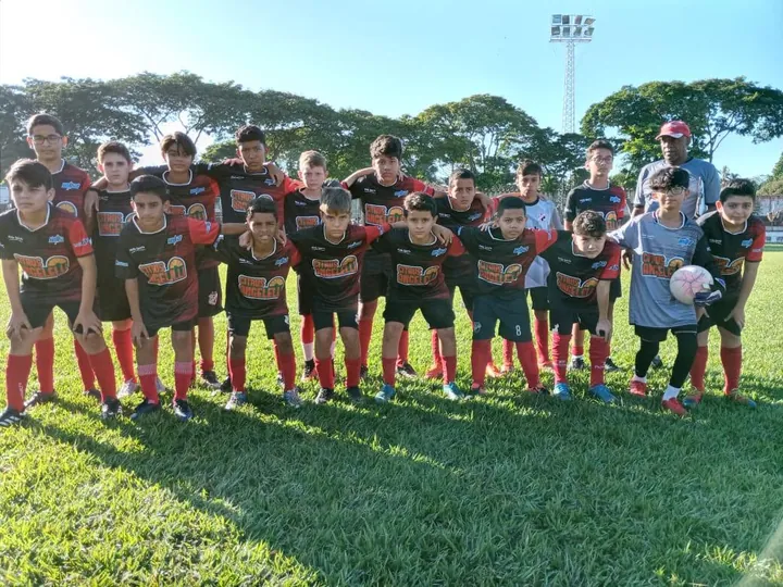 Equipe do CAB reunida no gramado, com uniformes vermelhos e pretos.